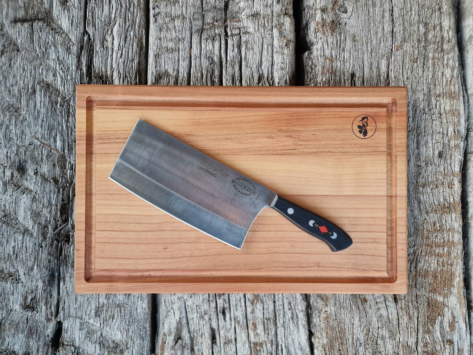Chopping Kochmesser von Dick auf einem Schneidebrett aus massivem Kirschbaum. Fotografiert auf historischen Eichenbalken.