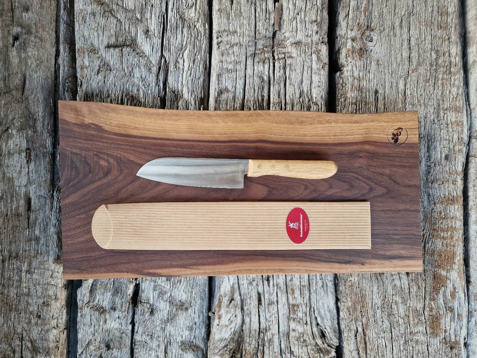 Geschenkset Vollholz Schneidebrett aus massivem Nussbaum mit Santoku Kochmesser mit Eiche Griff, fotografiert auf historischen Eichenbalken.