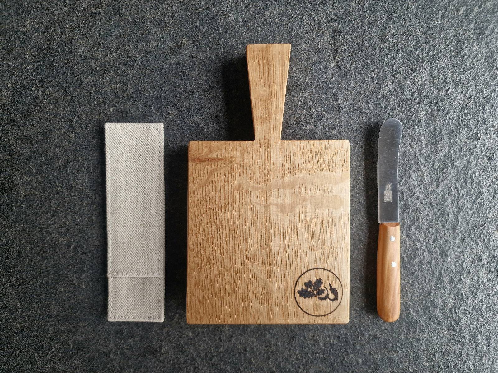 Kräuterbutter Brett in der Mitte. Links ein Windmühlenmesser Leinen Etui. Rechts ein Windmühlenmesser Beilegemesser.