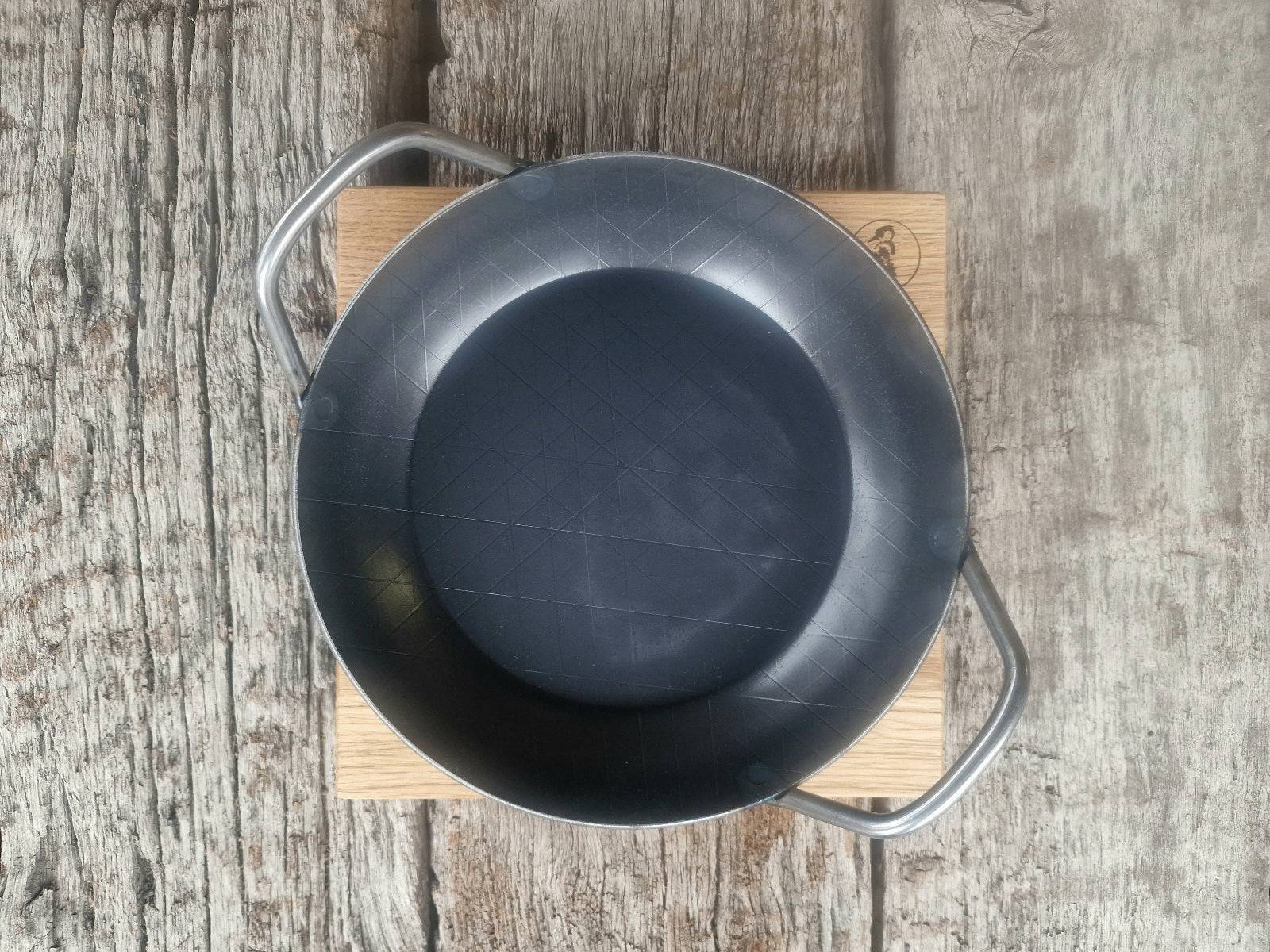 Von oben eine Servierpfanne aus Eisen auf einem Holz Topfuntersetzer.