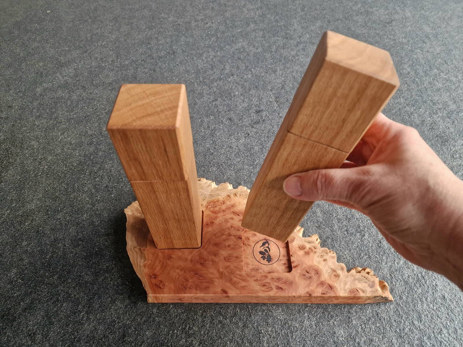 Eine Hand hält die Salzmühle hoch. Die Pfeffermühle steht auf einem Holz Untersetzer aus Eukalyptus Goldfield