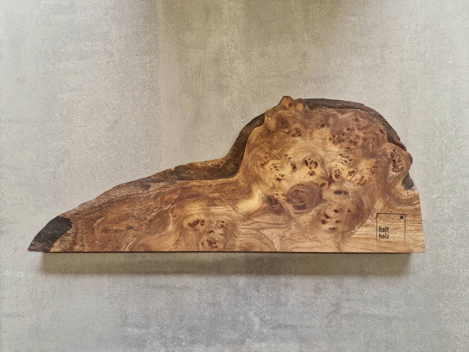 Unikat Edelholz Messerleiste aus Maserulme an einer Betonwand.