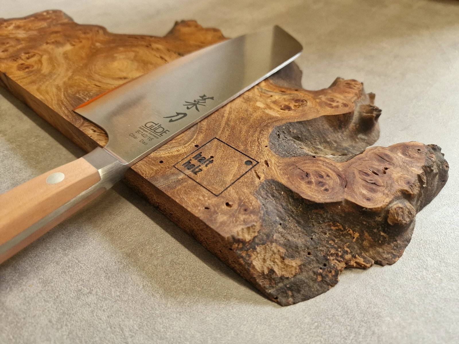 Detailansicht eines magnetischen Messerhalters aus Maserulme mit einem chinesischen Kochmesser von Güde.