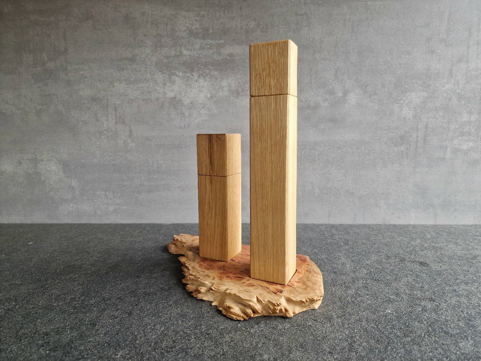 Vorne im Bild die hohe Pfeffermühle, dahinter die kleinere Salzmühle, beides aus Eiche. Die Mühlen stehen auf einem Untersetzer aus Goldfield