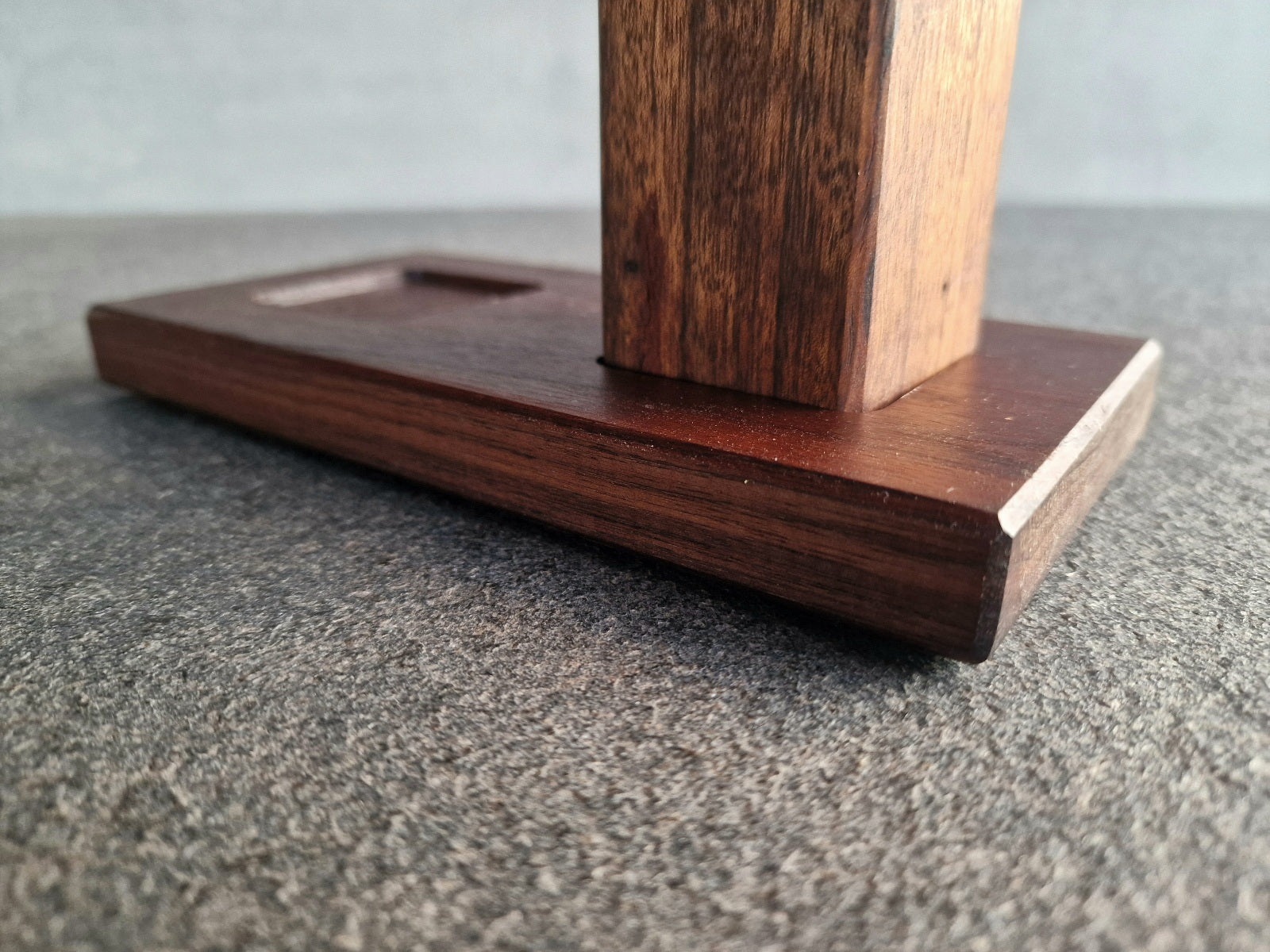 Nahaufnahme vom unteren Teil einer Salzmühle auf ein Holztablett aus Nussbaum.