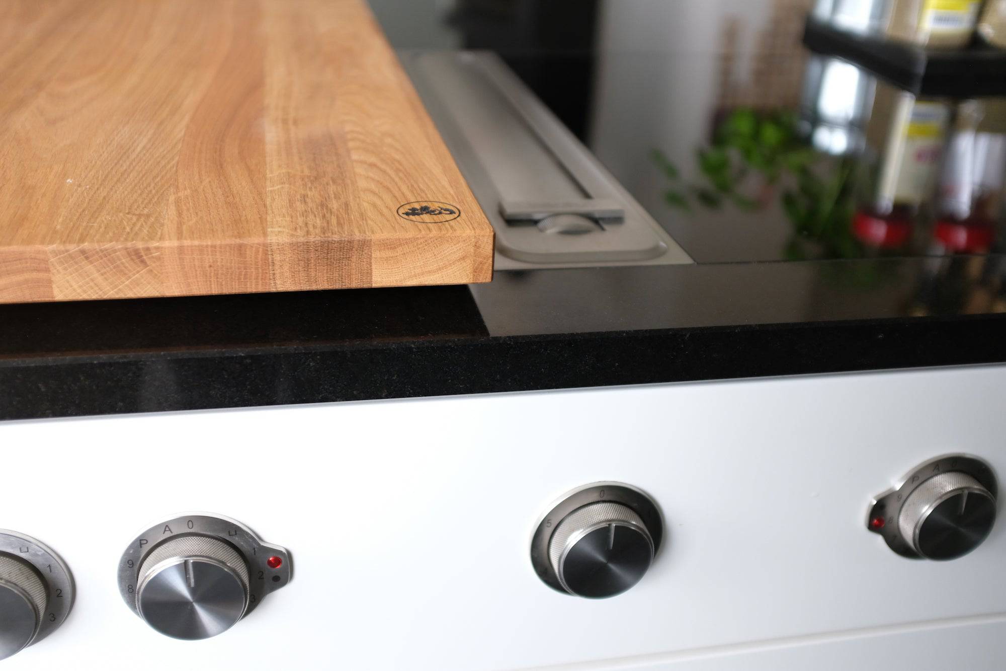 Detailansicht Herdabdeckung aus massiver Eiche auf einem Herd mit Down Air Dunstabzug.