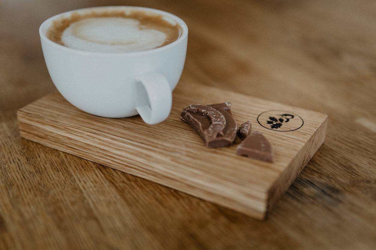 Cappuccino in einer weißen Porzellantasse auf einem Eiche Tablett.
