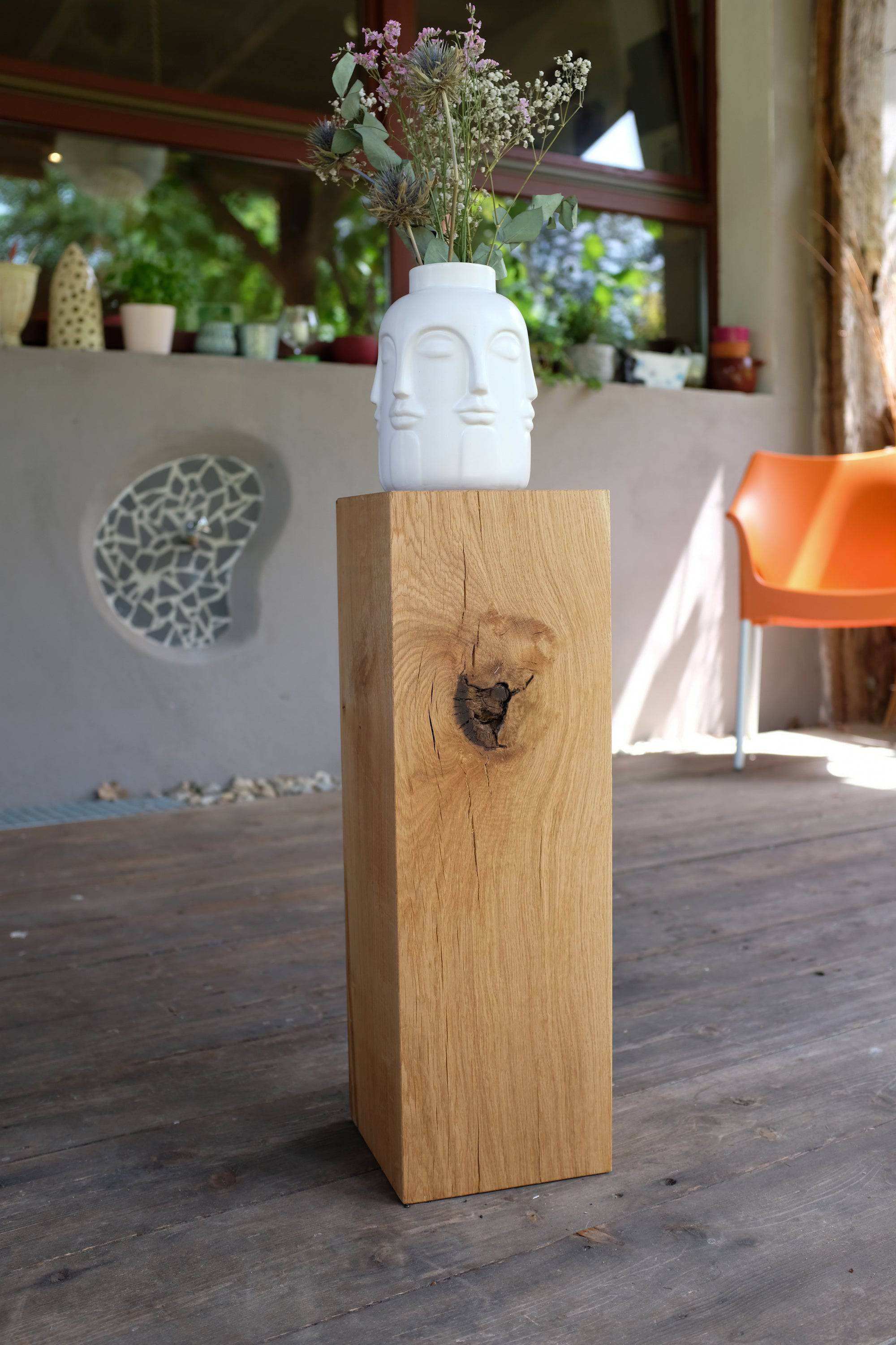 Eine 60 cm hohe Säule aus Eiche auf der ein weißer Design Blumentopf mit Blumen steht