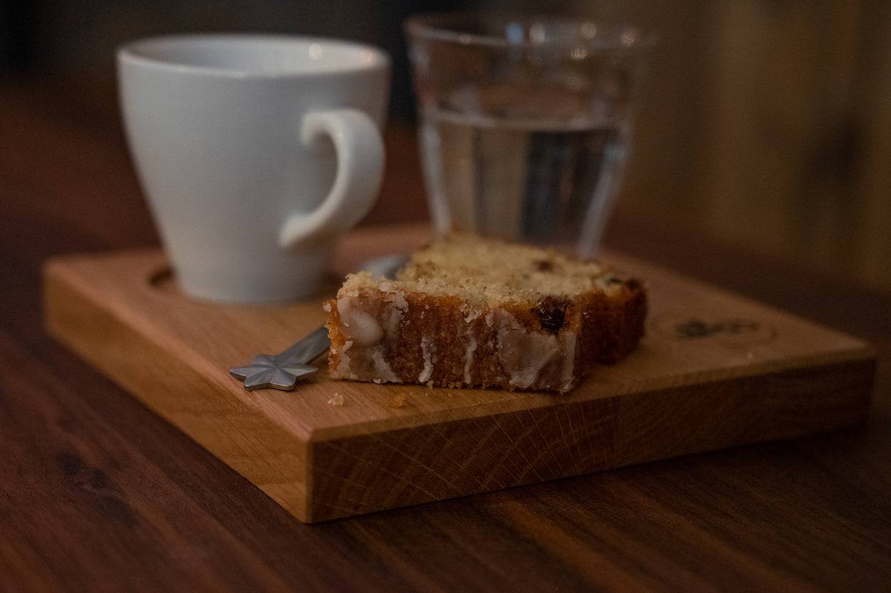 Nusskuchen auf einem Espresso-Holz-Tablett. Mit einer Tasse und einem Glas Wasser.