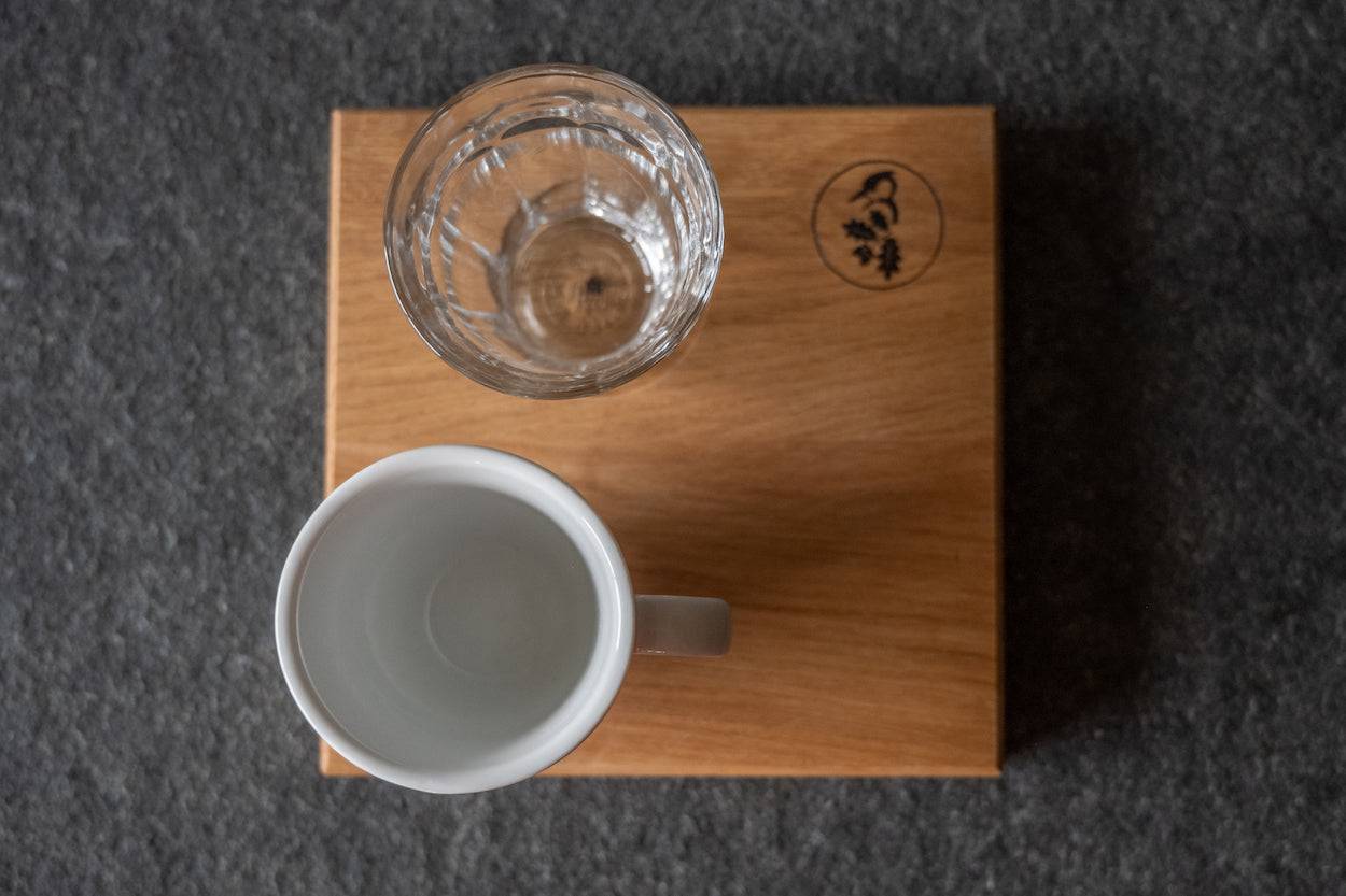 Espressotablett aus Eiche mit Glas und Tasse von oben , auf einer Steinplatte.