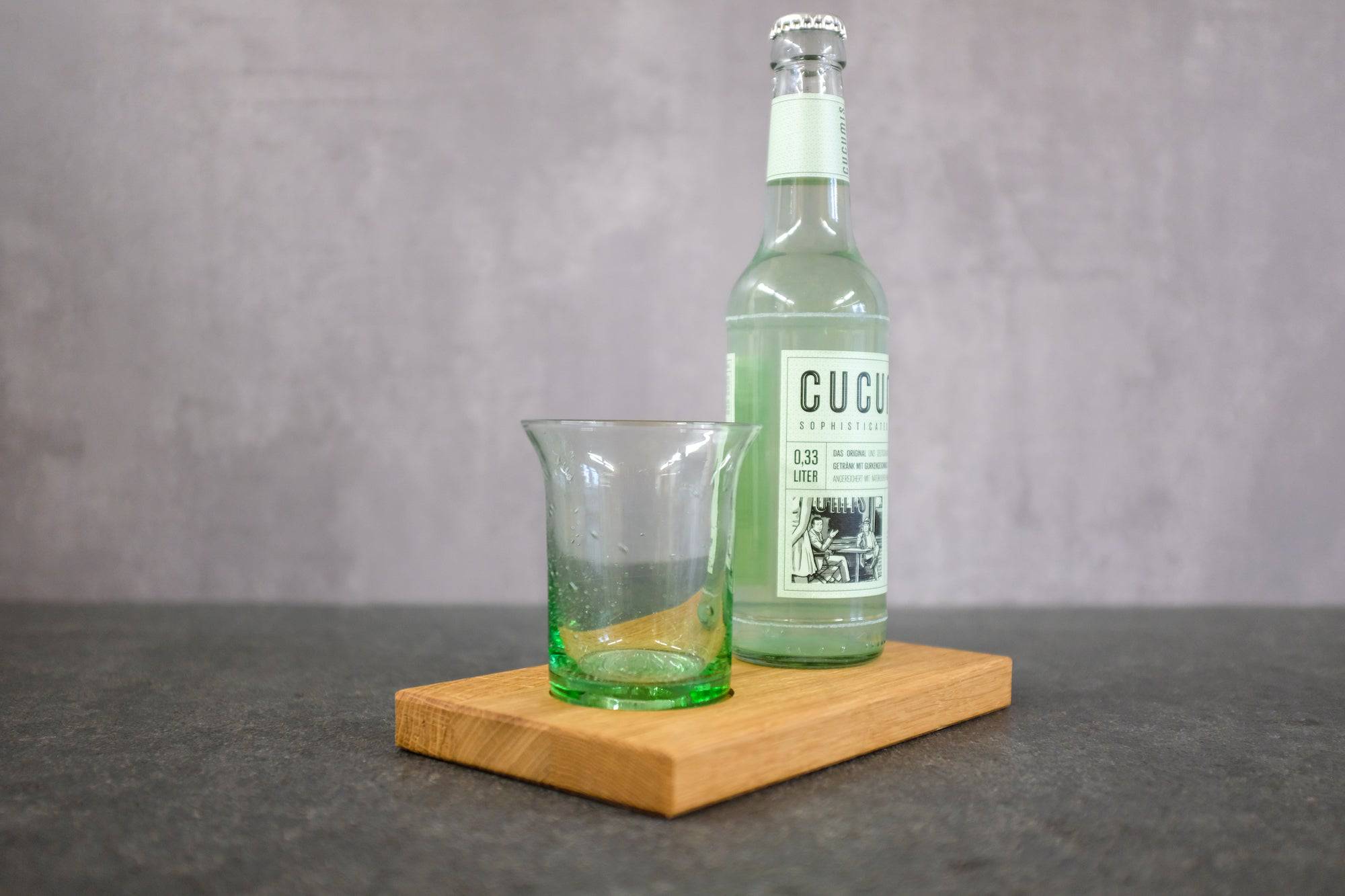 Farbglashütte Lauscha Goetheglas mit einer Gurkenlimonade auf einem Holzbrett.