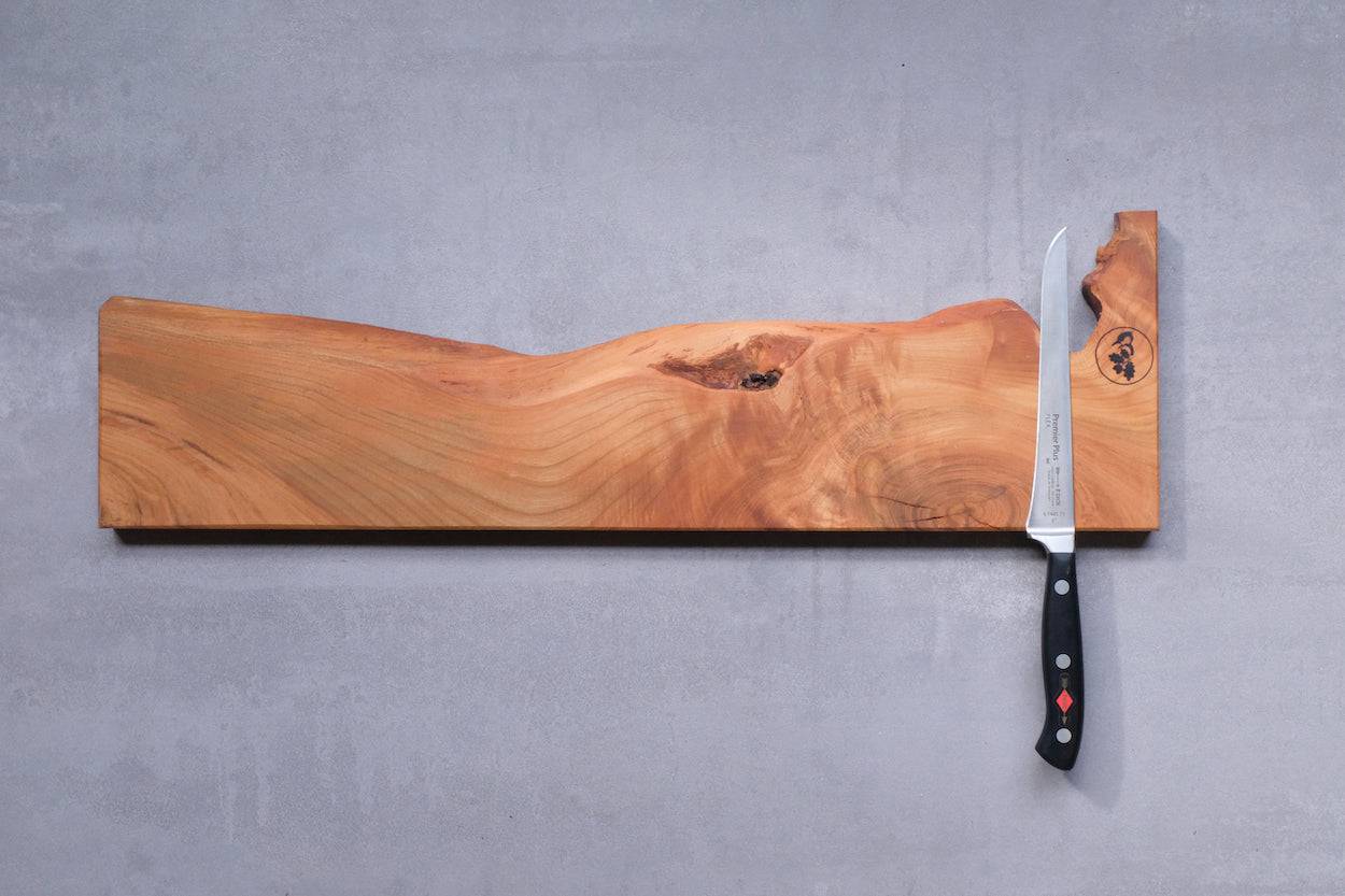 Kirschbaum Messerleiste mit einem Ausbeinmesser, an einer Betonwand montiert