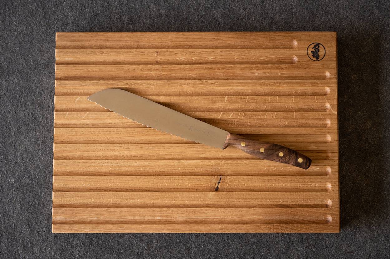 Grandmoulin Brotmesser mit Griff aus Walnuss liegt auf einem Spessartbrett Brotbrett