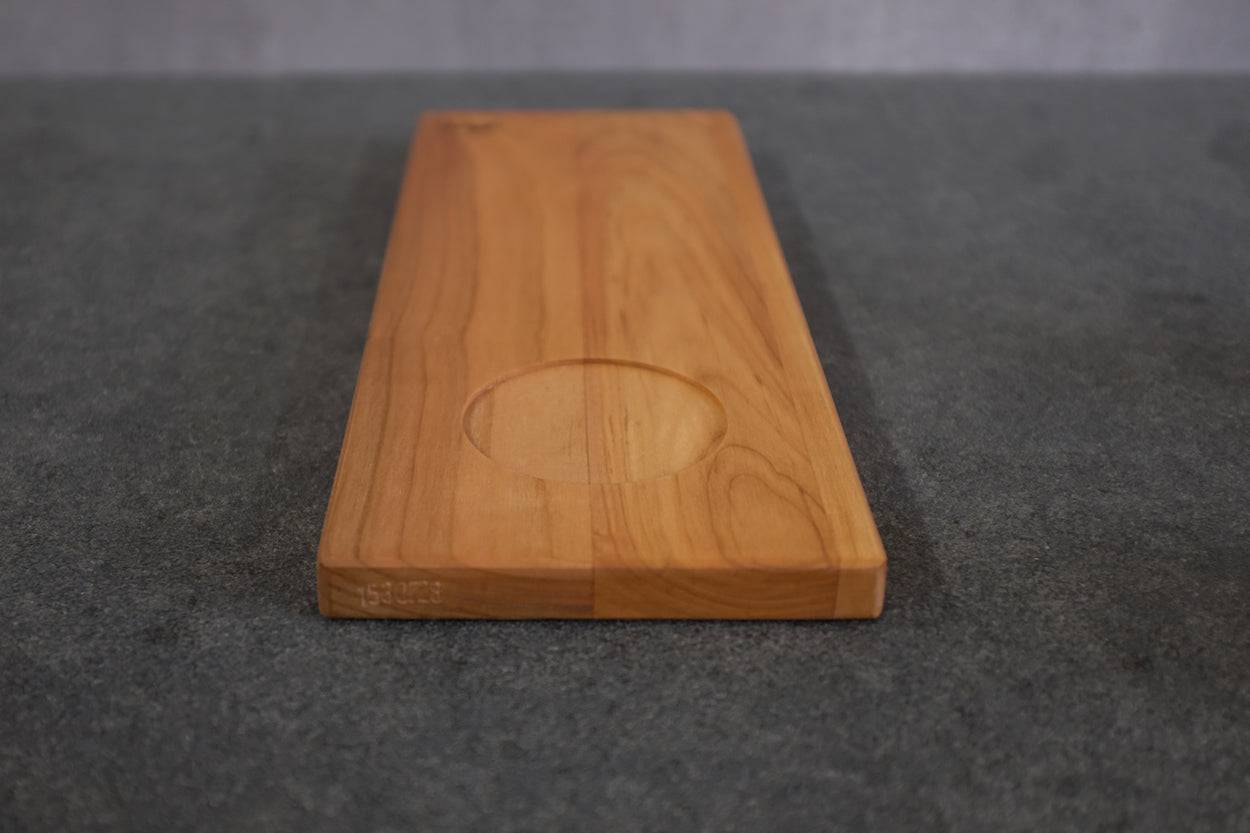 Holzteller in Kirsche massiv mit einer Vertiefung für einen Pott Kaffee in Frontalansicht.