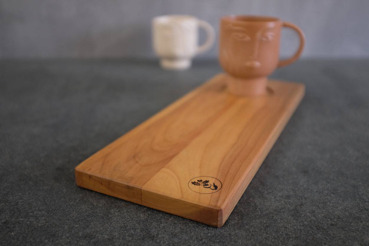 Rechteckiger Holzteller aus Kirsche massiv mit einer großen Tasse in terracotta.