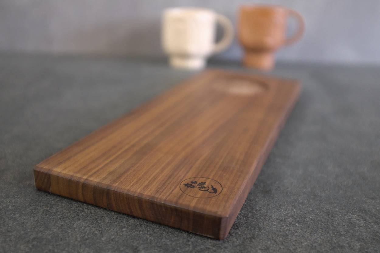 Frontalansicht eines Holz Tabletts aus Nussbaum. 2 Tassen im Hintergrund.