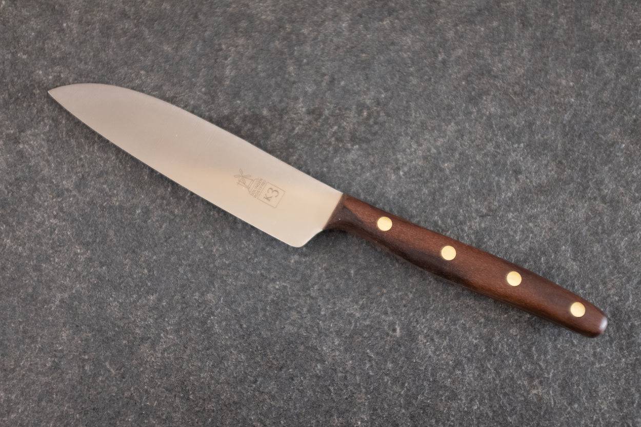 K3 Kochmesser mit Walnuss-Griff auf einer Steinplatte liegend.