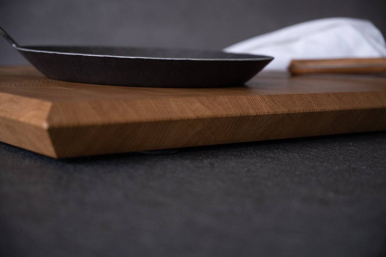 rechteckiger Schneideblock mit schrägen Kanten aus Eiche Hirnholz dekoriert mit Pfanne Messer und Tuch