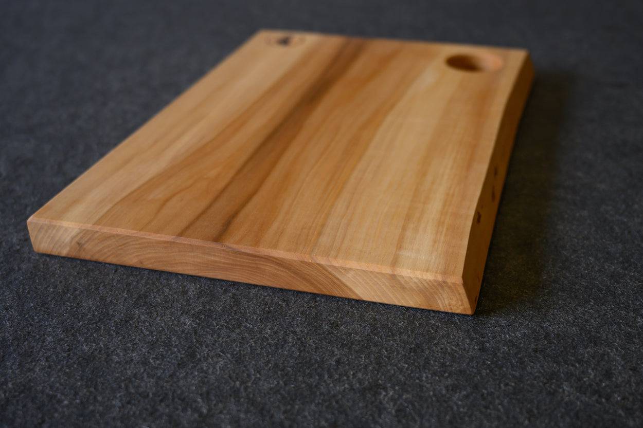 massives Brotzeitbrett aus einem Stück Vogelbeere und einem Loch für ein Ei