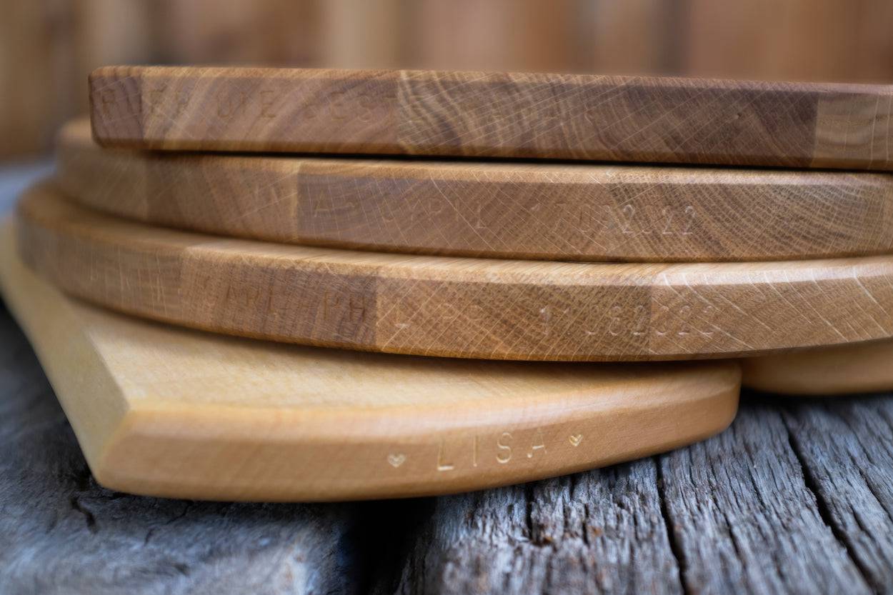 Von Hand eingeschlagener Namen und Hochzeitsdatum in einem massiven Holzbrett aus Eiche.