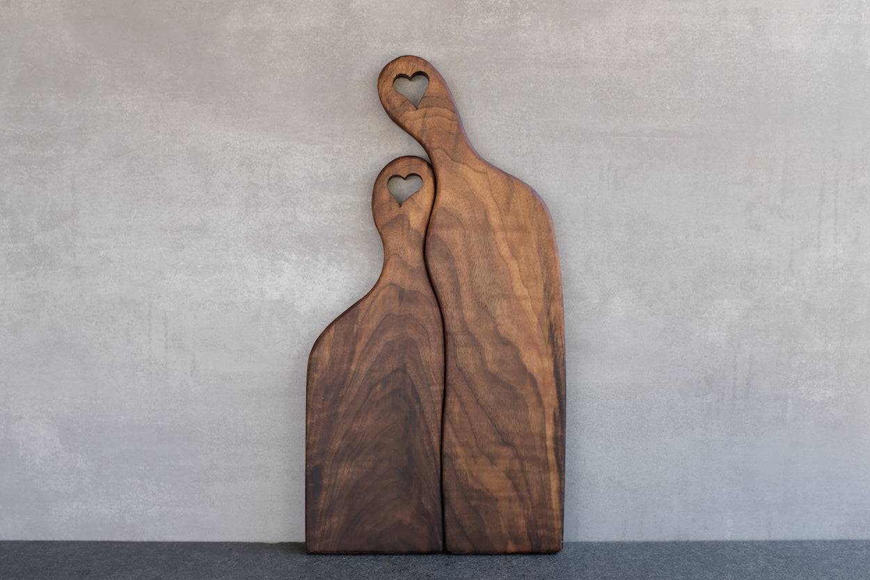 Rückseite Hochzeitsbrett mit Herz im Stiel, 2-teilig, massiver Nussbaum, an einer Betonwand angelehnt.