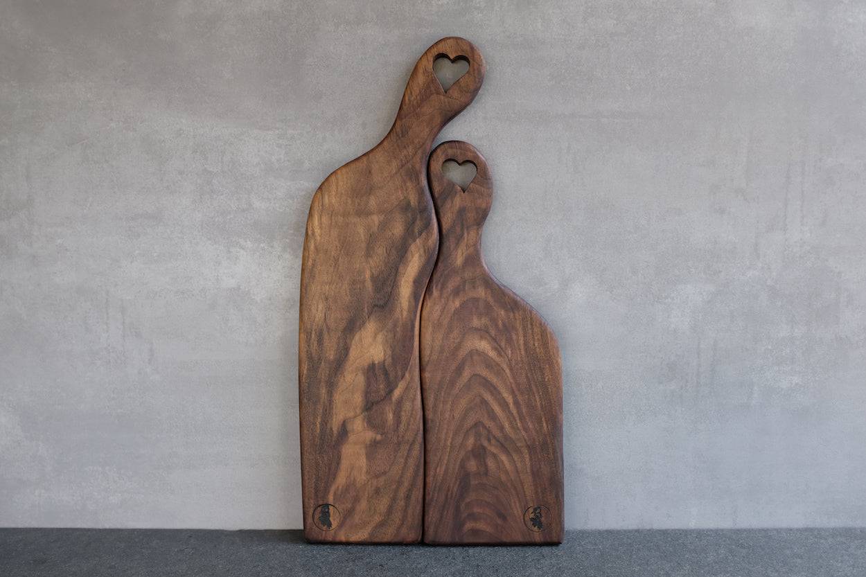 Hochzeitsbrett, Partnerbrett, 2 teilig, aus Vollholz Nussbaum, Unikat, an einer Wand anlehnt.