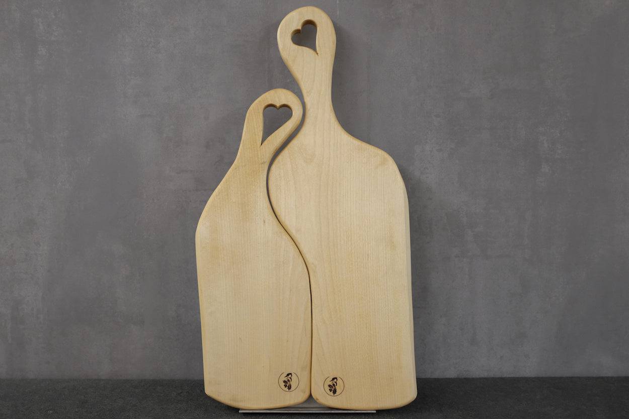 Partnerbrett, anschmiegsam, mit Stiel in Herzform. Aus massiver Birke an einer Betonwand angelehnt.