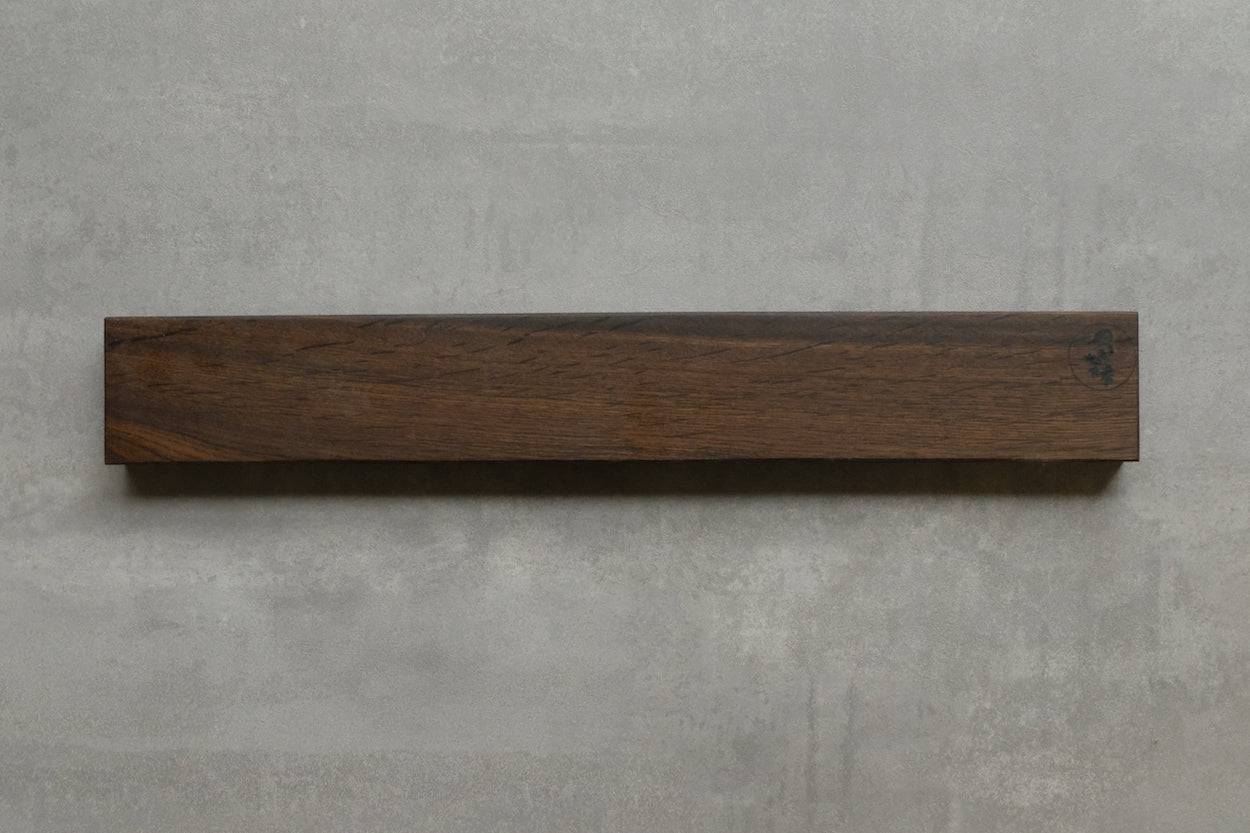 Magnetischer Messerhalter aus Räuchereiche an einer Betonwand montiert.
