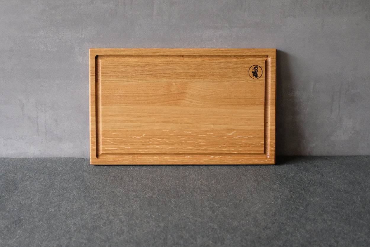 Schneidebrett mit Saftrinne Eiche an einer Betonwand angelehnt.