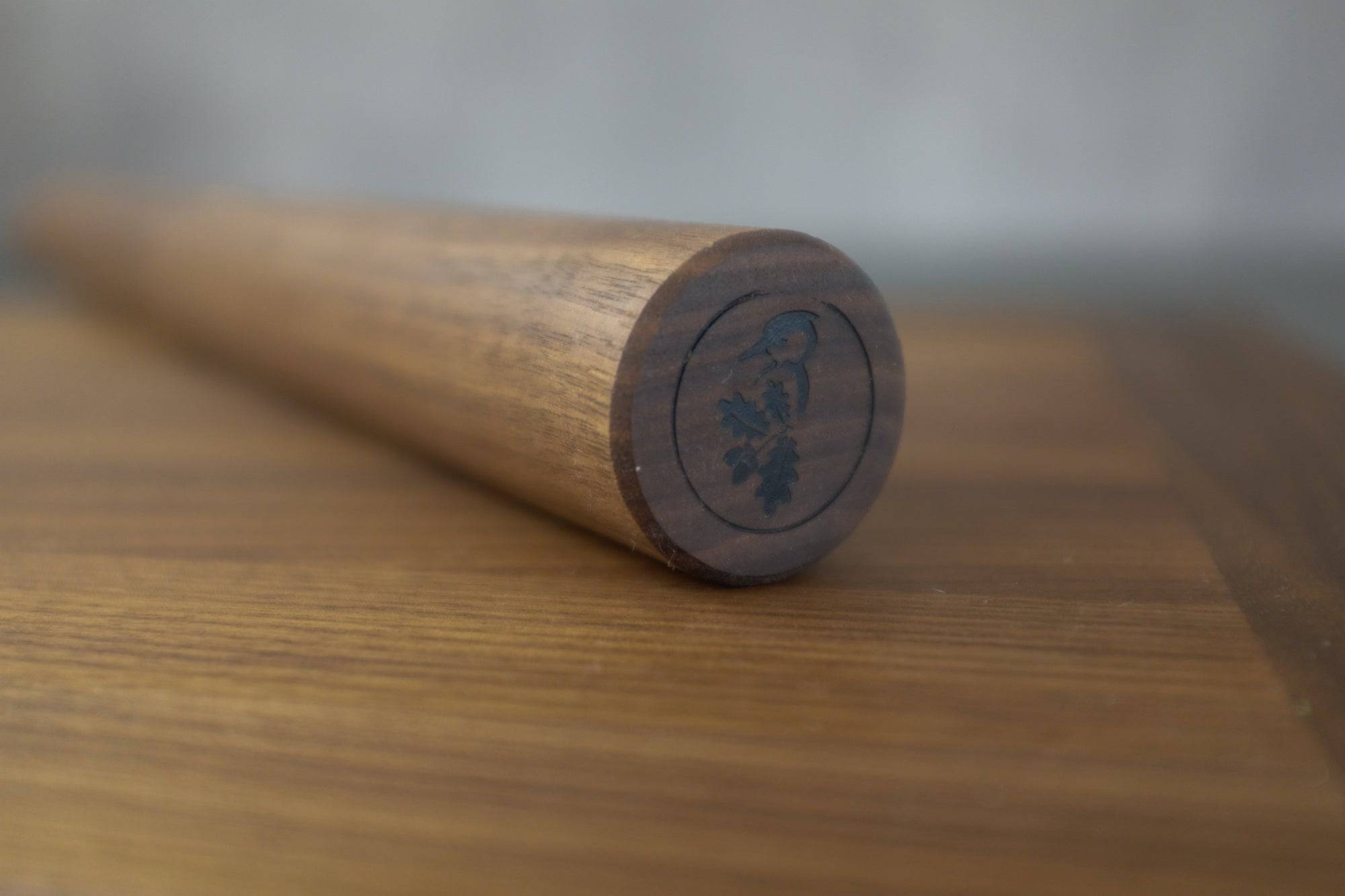 Frontalansicht einer Teigrolle aus massivem Nussbaum auf einem Backbrett aus Nussbaum.