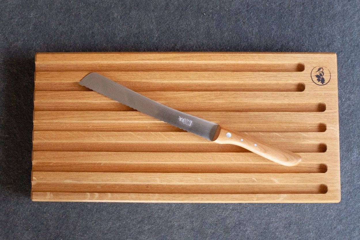 Brotsägemesser mit Carbonklinge 34,5 cm lang Griff aus Kirschholz liegt auf Brotbrett