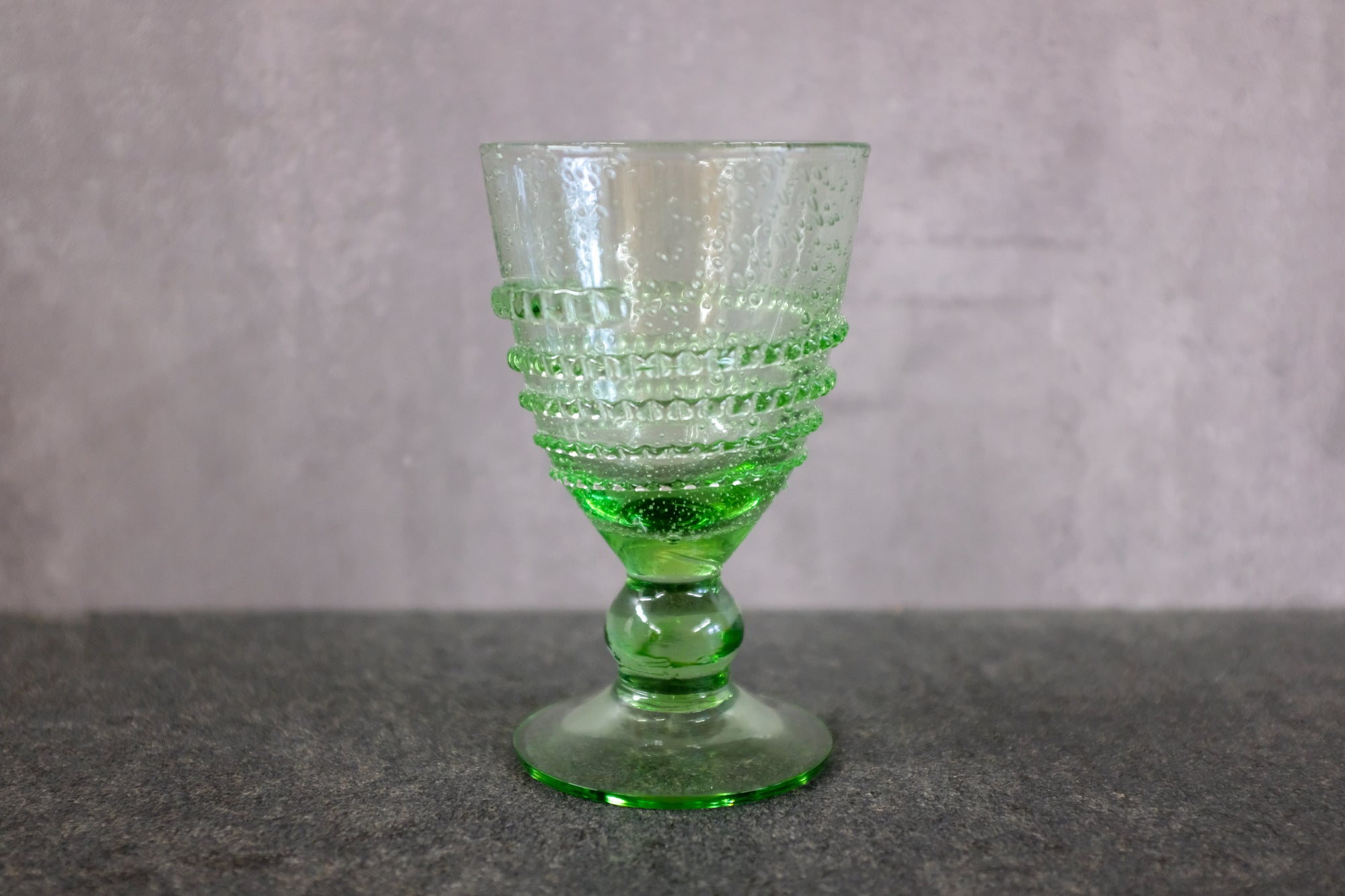 Antikes Weinglas aus Thüringer Waldglas auf einer Steinplatte.