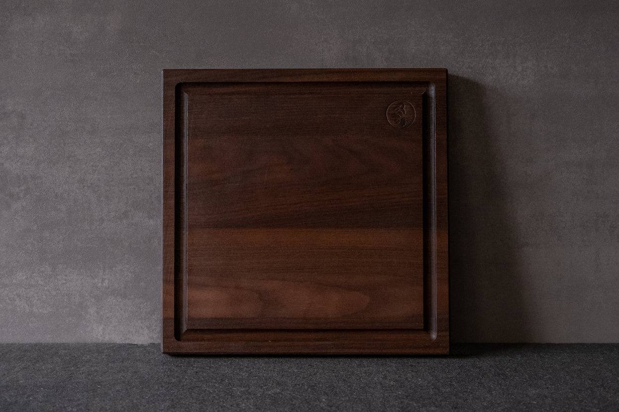 Quadratisches Schneidebrett mit Saftrille aus Nussbaum massiv.