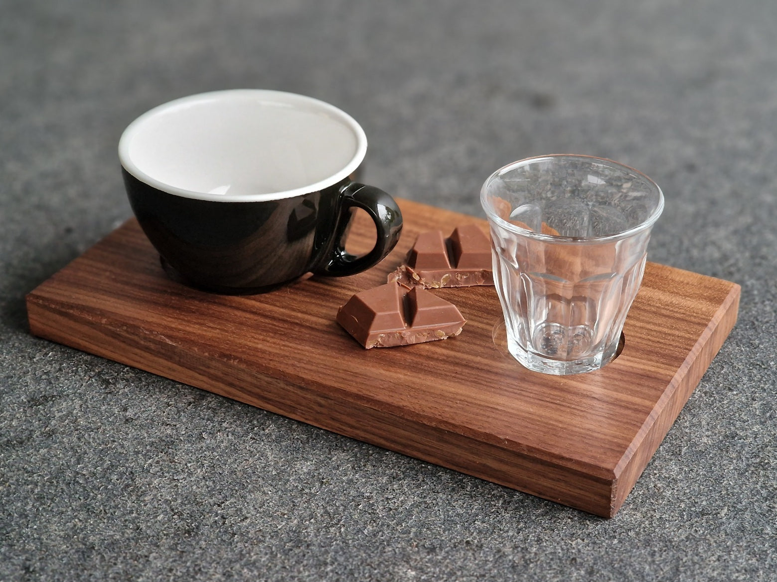 Nussbaum Holz Tablett für eine Cappuccinotasse und eine Wasserglas. Mit Schokolade dekoriert.