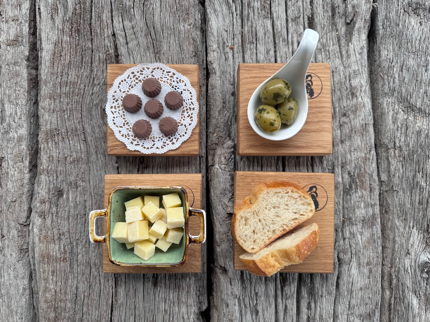 Kleine Eiche Untersetzer auf alten Eichenbalken. Dekoriert mit Pralinen, Oliven, Käse und Baguette.