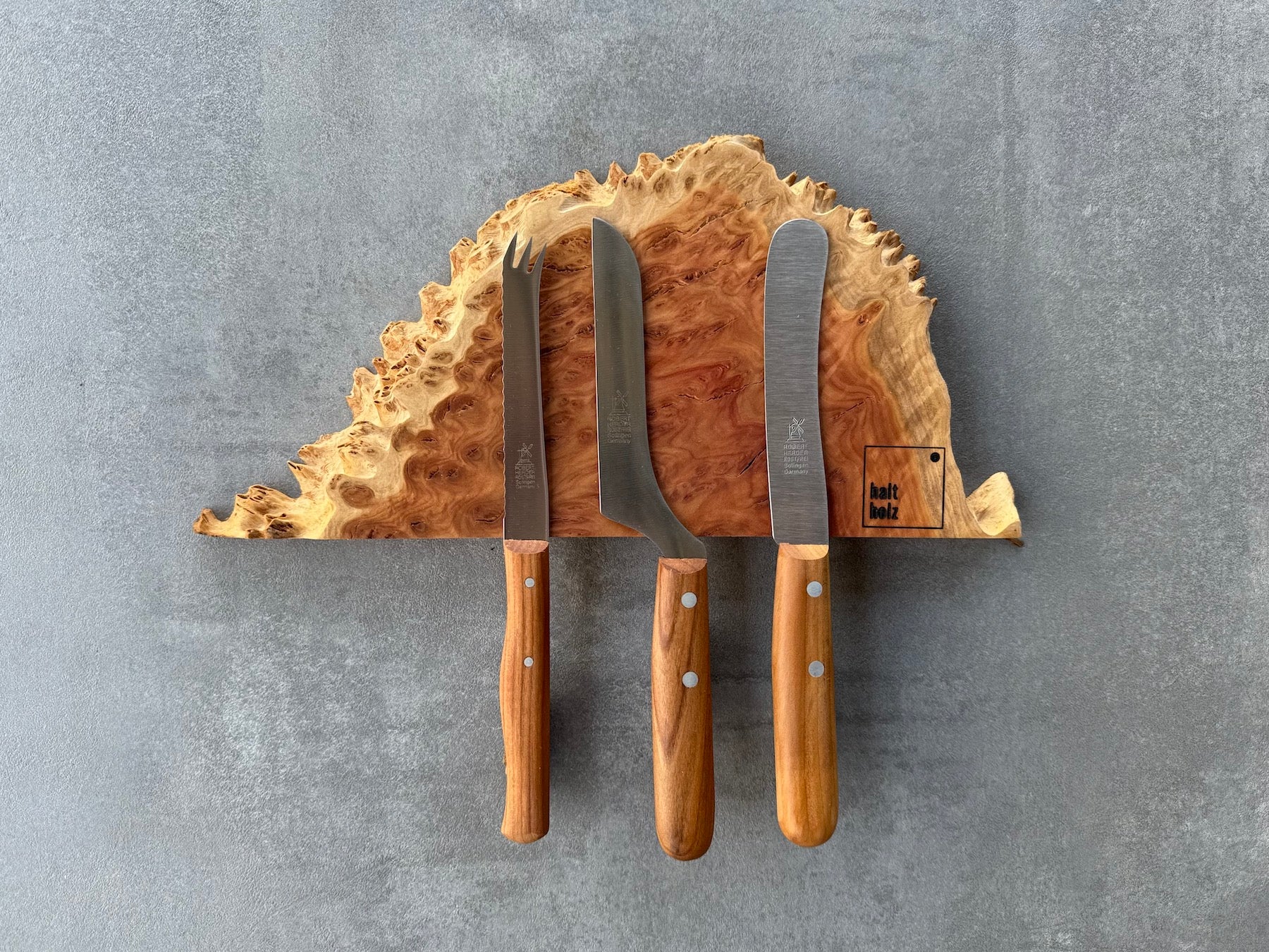 Australischer Goldfield Edelholz Messerleiste für 3 Messer an einer Betonwand. Dekoriert mit 3 Windmühlenmesser Kochmesser.
