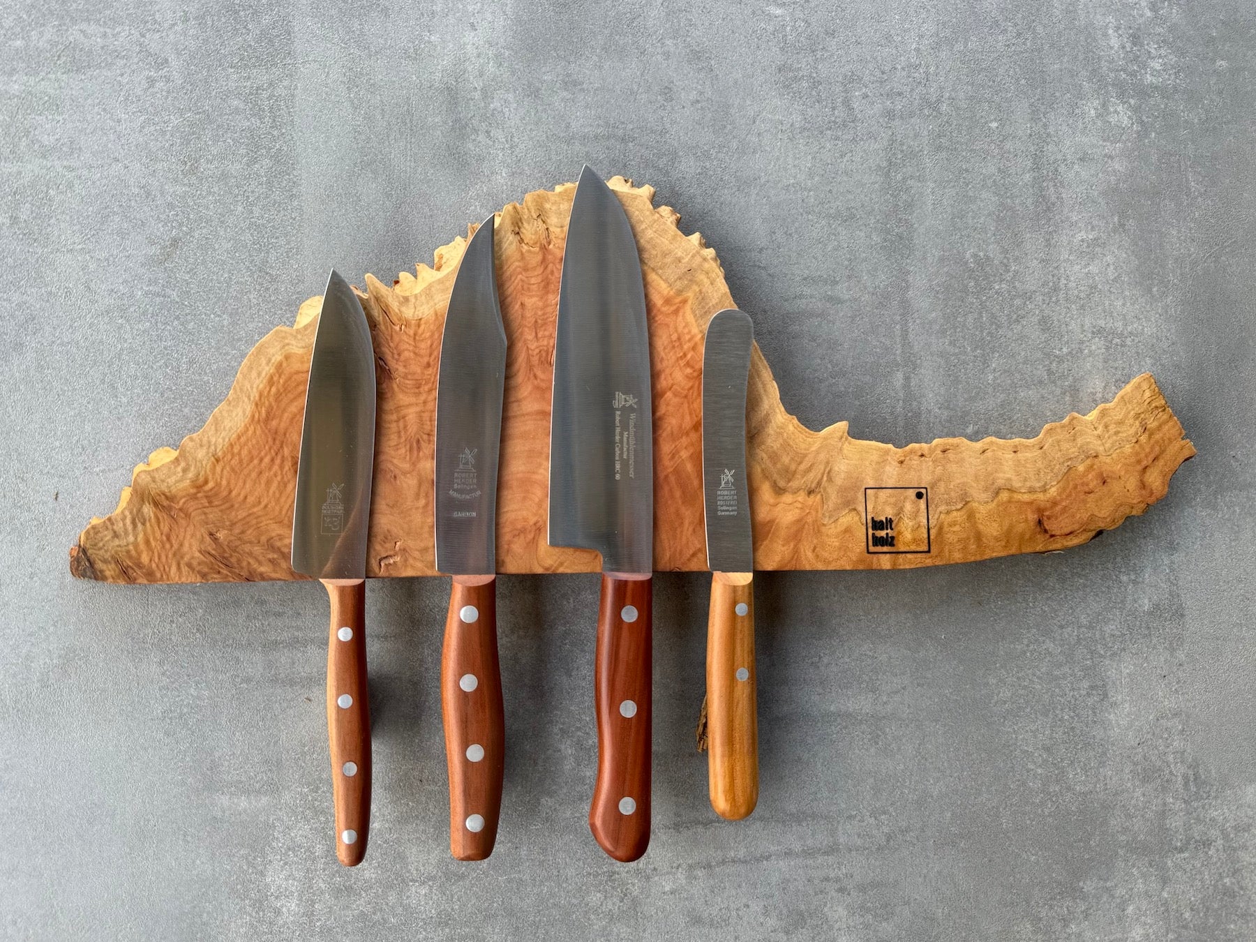 Australischer Goldfield Edelholz Messerleiste für 4 Messer an einer Betonwand. Dekoriert mit vier verschiedenen Windmühlenmesser Kochmesser.