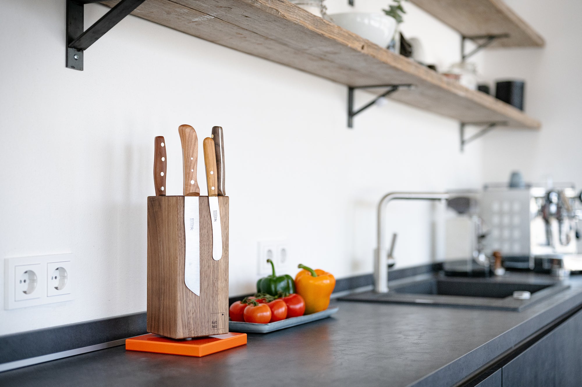 Drehbarer magnetischer Messerblock aus massivem Nussbaum mit einem orangenem Stahlsockel in einer hellen Küche