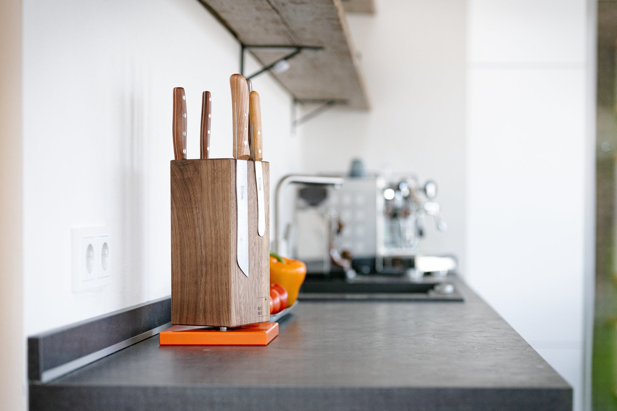 In einer hellen Küche:Drehbarer magnetischer Messerblock aus massivem Nussbaum mit einem orangenem Stahlsockel. Mit Messern von DICK und Windmühlenmesser.
