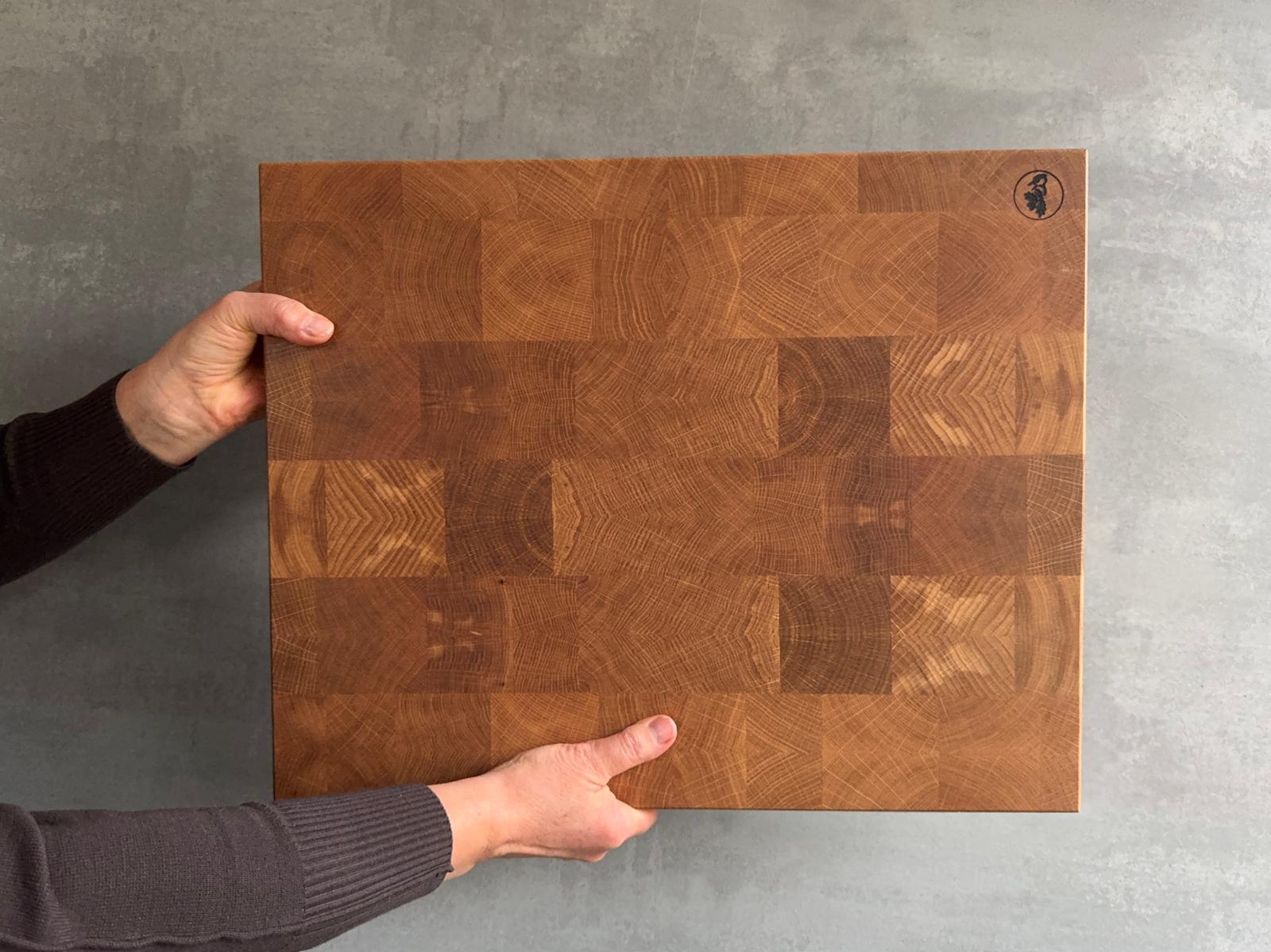 Jemand hält einen Eiche Hirnholz Schneideblock hoch