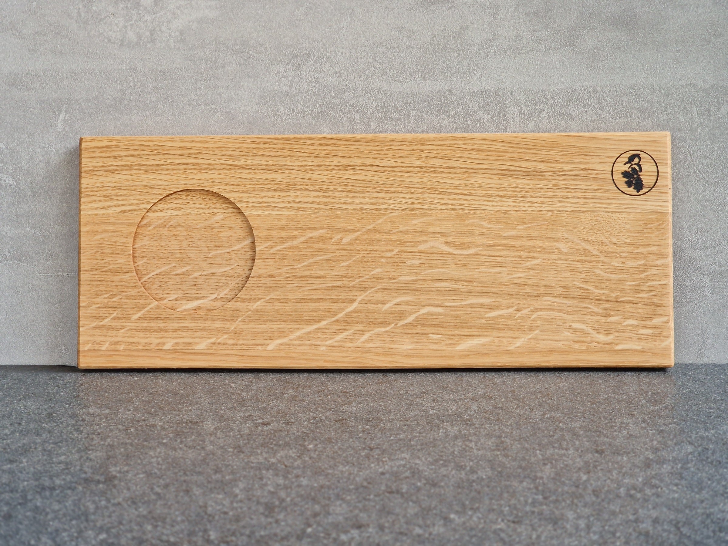 Eiche Holz Tablett mit einer Vertiefung für eine große Tasse an einer Betonwand angelehnt. 
