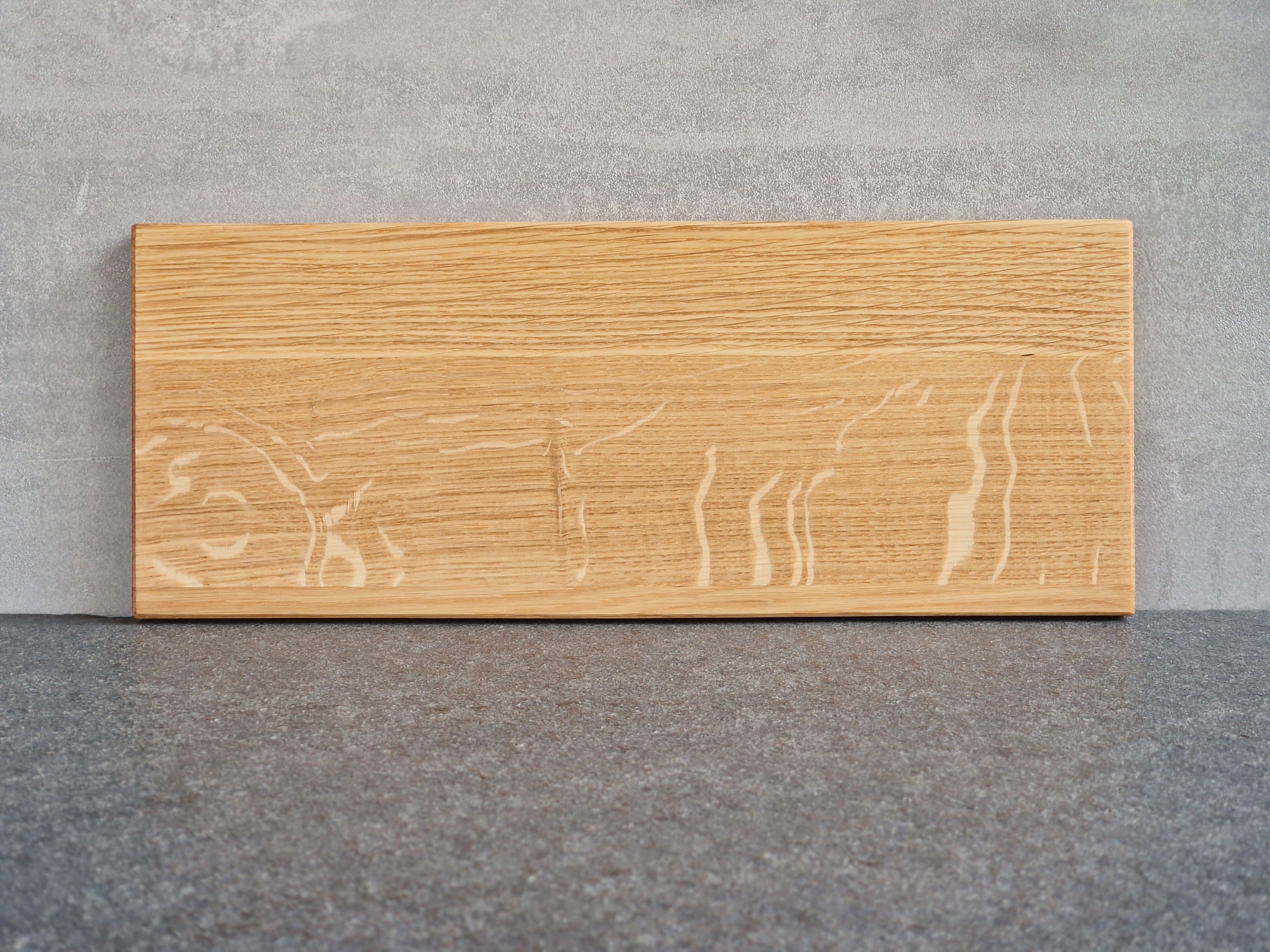 Rückseite Eiche Holz Tablett mit einer Vertiefung für eine große Tasse an einer Betonwand angelehnt. 