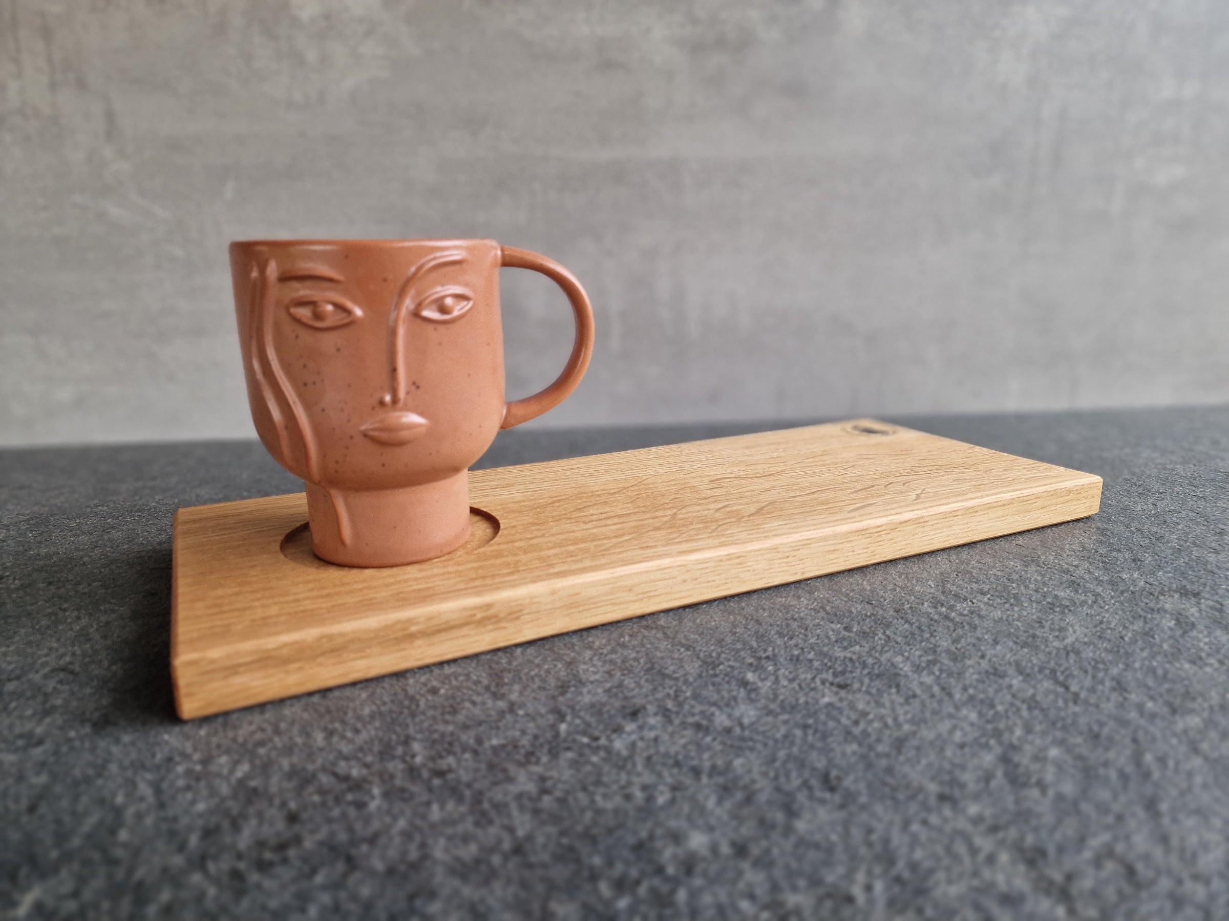 Ein Eiche Cappuccino Tablett mit einer Pott Tasse mit Gesicht auf einer Marmorplatte.