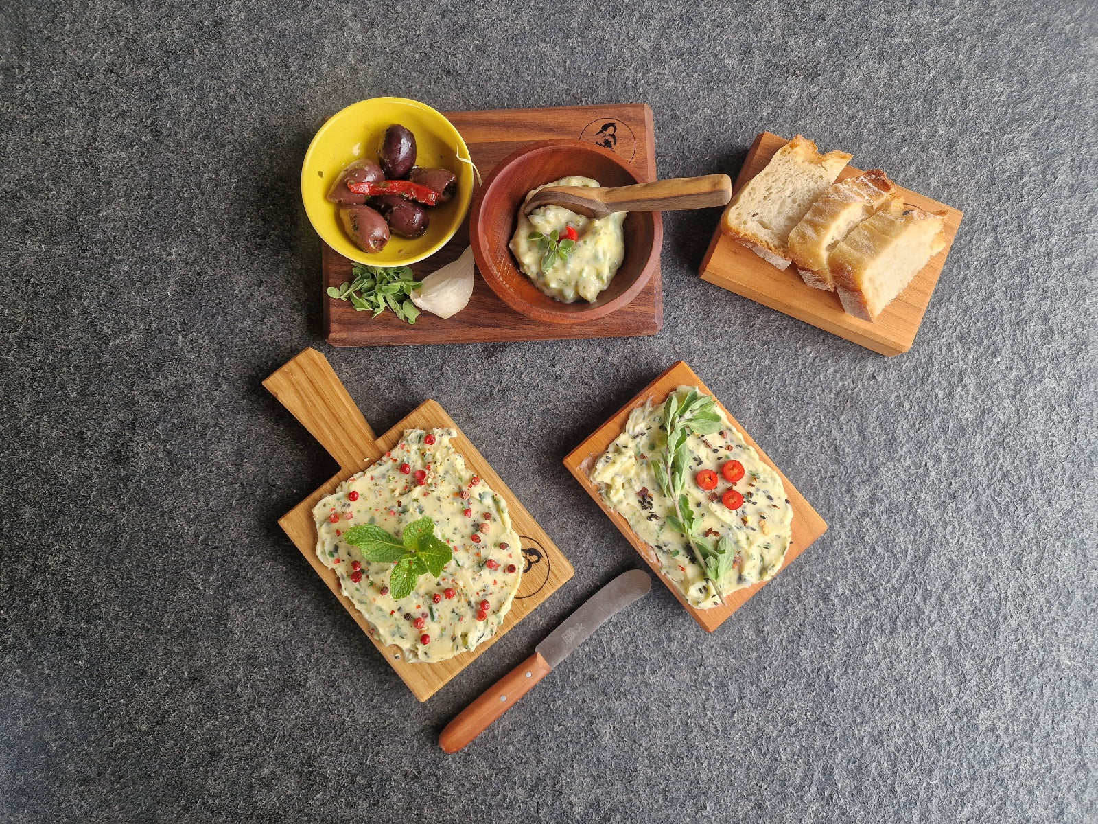 2 Butterboard Gerichte und Dinkelbrot Scheiben auf kleinen Holzbrettern angerichtet. Oliven und Kräuterbutter in einer Schale.