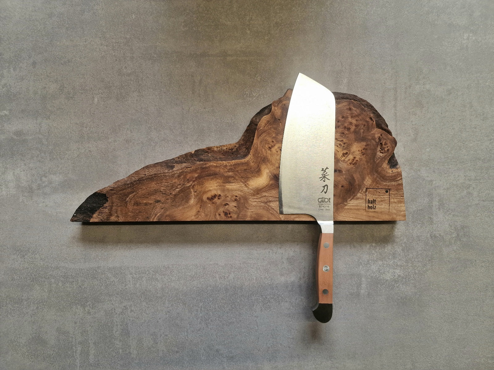 Edelholz Messerleiste aus Maserulme mit einem Güde Kochmesser Alpha an einer Betonwand.