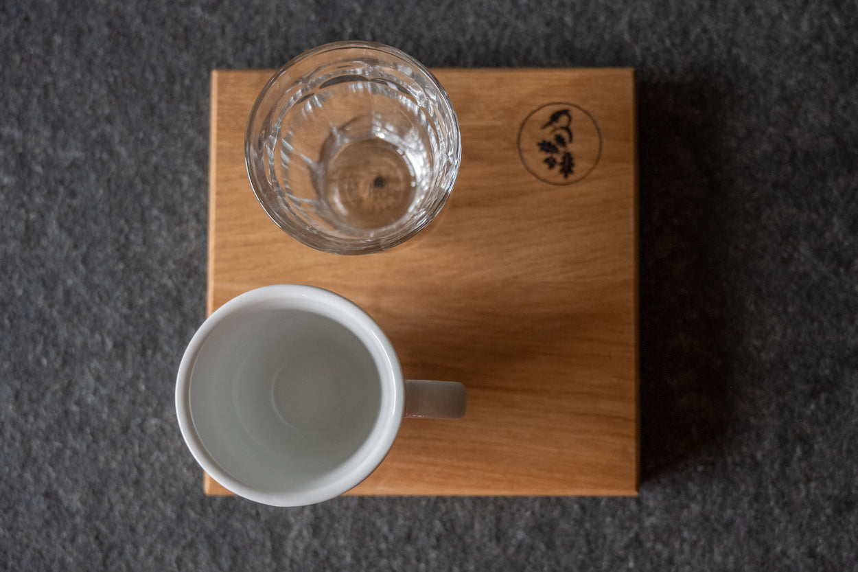 Espressotablett aus Eiche mit Glas und Tasse von oben , auf einer Steinplatte.