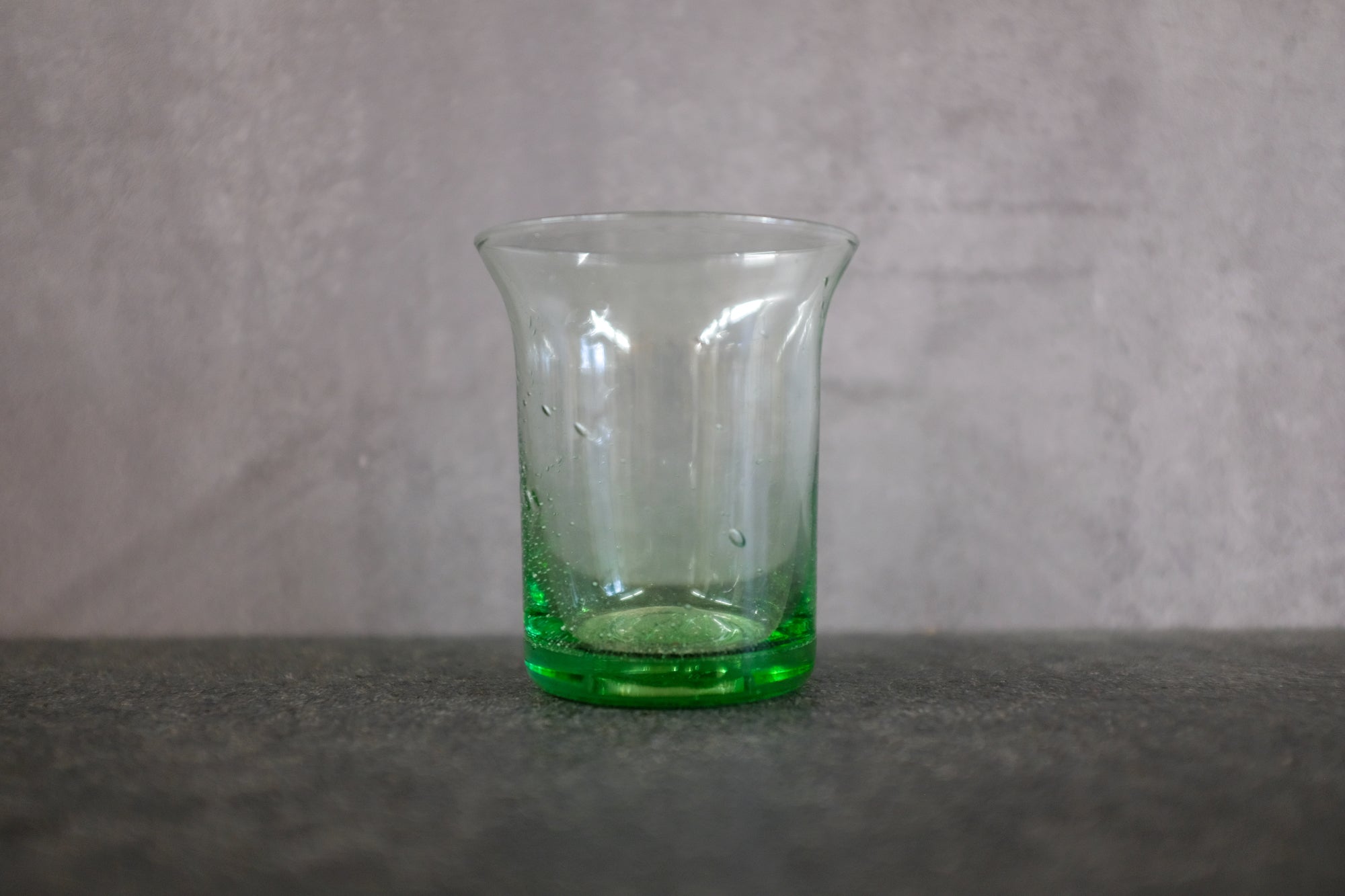 Trinkglas aus Thüringer Waldglas auf einer Steinplatte.