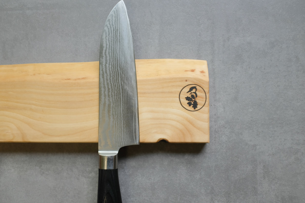 Detailaufnahme eines Vogelbeere Magnet Messerhalter mit einem Santoku Messer