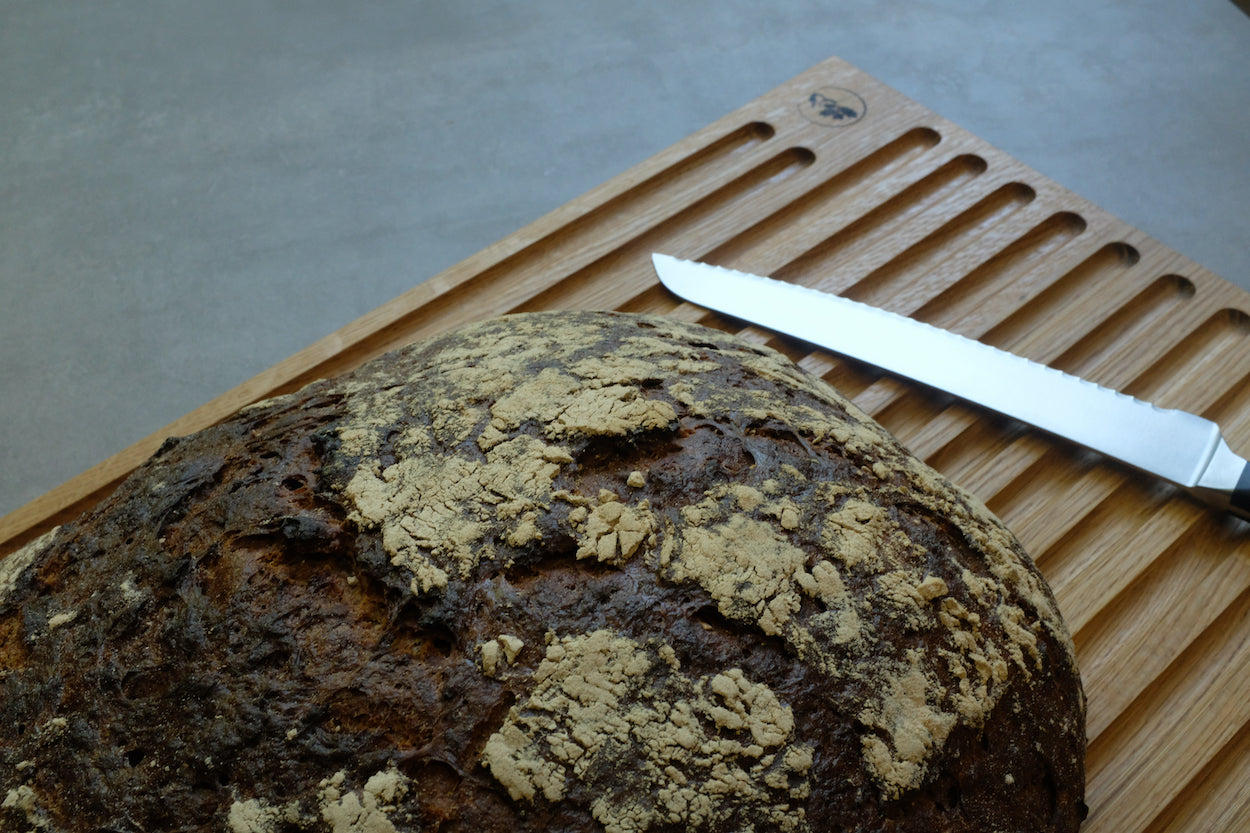 Detailaufnahme von einem Brotbrett mit einem Brot und einem Messer.