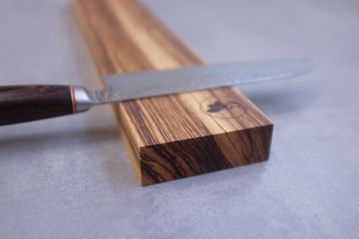 Detailaufnahme von einem Zebrano Holz Messerhalter mit einem Santoku Messer.